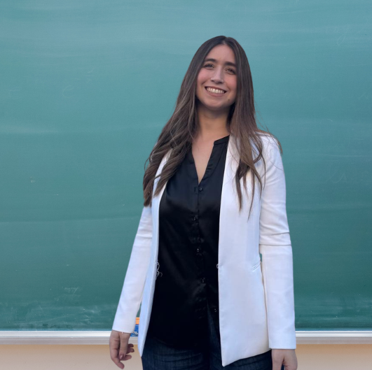 María smiling in front of a classroom board