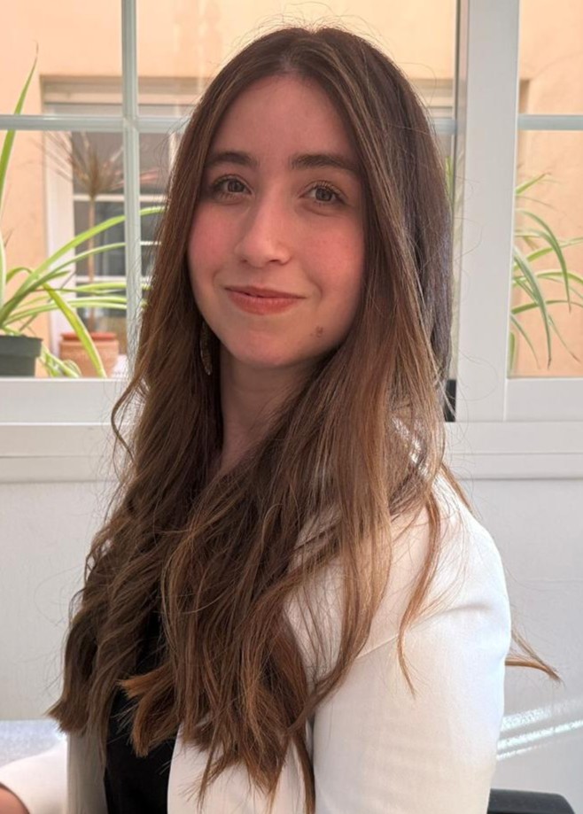 María smiling in front of a classroom board